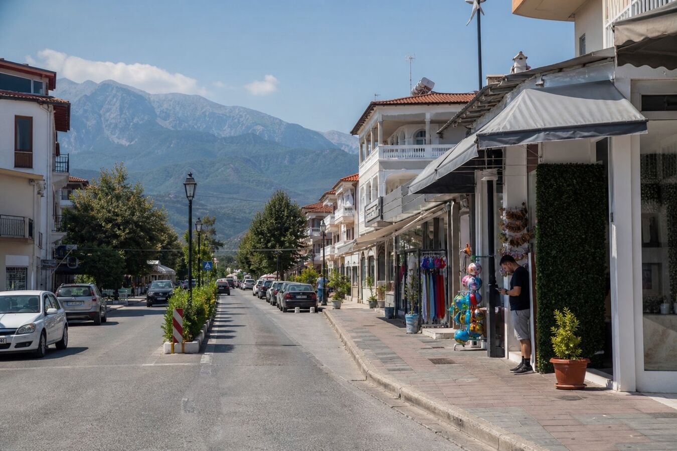 Παραλιακή στη Λεπτοκαρυά με τοπικά μαγαζιά και επισκέπτη που κοιτάει κινητό έξω από βιτρίνα.
